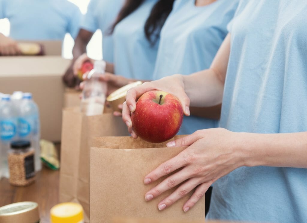 Volunteers packing food and drinks into paper bags